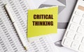 Yellow note with text critical thinking on financial documents with pen and calculator Royalty Free Stock Photo