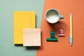 Yellow notebook and pen, clip, cup of milk on green and red desk background. study and workspace. flat lay, top view, copy space Royalty Free Stock Photo