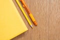 Yellow notebook, yellow pen, yellow pencil on a wooden table surface. Stationery of the same color. Office supplies. Free space