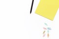 Yellow Notepad, black pencil, and colored paper clips on a white background. Minimal business concept. Flat law. Royalty Free Stock Photo