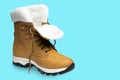 Yellow nubuck boot, with white fur, on a turquoise background, shoes unlaced, concept, isolate Royalty Free Stock Photo