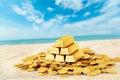 Gold bars and coins on sand beach