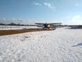 Yellow old biplane plane on a dirt runway in winter on a Sunny day Royalty Free Stock Photo
