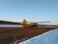 Yellow old biplane plane on a dirt runway in winter on a Sunny day Royalty Free Stock Photo