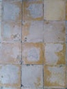 Yellow old-fashioned floor tiles that are fading because they are decades old