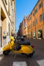 Yellow old fashioned scooter on street in Rimini with many-coloured houses, ancient city center. Vacation in beautiful Italy,