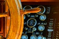 Yellow, old, lacquered, wooden steering wheel on a marine yacht, sensors and pointers with arrows in the background Royalty Free Stock Photo