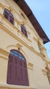 Yellow old style Thai building with brown wooden window. Royalty Free Stock Photo