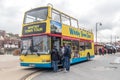 Yellow open top double decker sightseeing Whitby Town Tour bus with passengers waiting to board