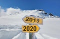 yellow panel 2019 and 2020 in front of snowy mountain landscape under blue sky