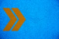 Yellow orange arrows signs pointing right direction over intense bright blue color stucco rough wall background