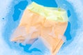 Yellow and orange baby shorts soak in baby laundry detergent water dissolution, washing cloth, Laundry concept