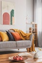 Yellow, orange, black and brown pillows on comfortable grey scandinavian sofa in bright living room interior with abstract Royalty Free Stock Photo