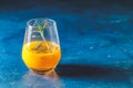 Yellow orange cocktail with tangerine and rosemary in glass on dark blue concrete background, close up. Christmas and New Year