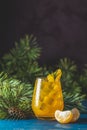 Yellow orange cocktail with tangerine and rosemary in glass on dark blue concrete background decorated pine branches with cones Royalty Free Stock Photo