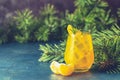 Yellow orange cocktail with tangerine and rosemary in glass on dark blue concrete background decorated pine branches with cones Royalty Free Stock Photo