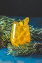 Yellow orange cocktail with tangerine and rosemary in glass on dark blue concrete background decorated pine branches with cones Royalty Free Stock Photo