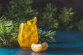 Yellow orange cocktail with tangerine and rosemary in glass on dark blue concrete background decorated pine branches with cones, Royalty Free Stock Photo