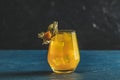 Yellow orange cocktail with tangerine and rosemary in glass decorated Physalis peruviana on dark blue concrete background , close Royalty Free Stock Photo