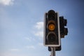 Yellow, orange color traffic light. Blue sky with few clouds background. Close up under view, copyspace. Royalty Free Stock Photo