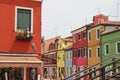 Yellow and orange houses in Burano, small houses on a Venetian island, colourful houses, Italy, flowers in pots, wooden shutters