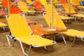 Yellow and orange sunbeds and umbrellas on a beach in Crete