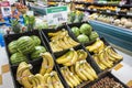 Yellow organic bananas and lush green organic watermelons in black baskets surrounded by colorful produce at the vegan market Royalty Free Stock Photo