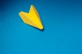 Yellow origami plane on a blue background.