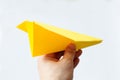 Yellow origami plane on a white background.