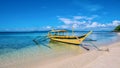 A yellow outrigger boat anchored in crystal clear water off a white sand beach in the Philippines. Royalty Free Stock Photo