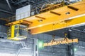 Yellow overhead crane with linear traverse and hooks in engineering plant shop Royalty Free Stock Photo