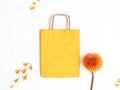 Yellow package on a white background with an orange flower, spring or summer decor. Top view, place for dough and logo Royalty Free Stock Photo