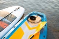 Yellow Paddle board and two surf boards on blue clean water surface background. Surfing and SUP boarding equipment in