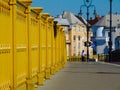 Yellow painted cast iron bridge railing in diminishing perspective with cyclist