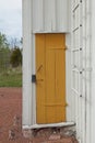Yellow painted door on a old white wood building. Royalty Free Stock Photo
