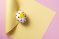 Yellow painted easter egg on yellow and pink background