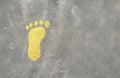 Yellow painted footprint on a gray asphalt background. Top view