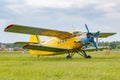 Yellow painted legendary soviet aircraft biplane Antonov AN-2 parked on a green grass of airfield against cloudy sky Royalty Free Stock Photo