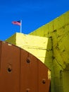 Yellow painted stone walls, wood door, and American flag with clear blue sky Royalty Free Stock Photo