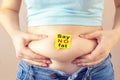 A yellow paper blank message is written Say no fat on belly with hands squeezes at the waist of a young woman in jeans. The Royalty Free Stock Photo