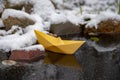 Yellow paper boat stuck in the ice, on a frozen puddle Royalty Free Stock Photo