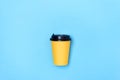 Yellow paper cup, light blue background. Coffee to go. Place for text on the right, left and above. Layout. Copy space. Minimalism