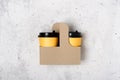 Yellow paper cups in craft cup holder and light gray concrete background. Flatlay. Coffee to go concept. Place for text around.