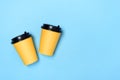 Yellow paper cups on a light blue background. Flatlay. Coffee to go concept. Place for text on the right. Copy space. Minimalism,