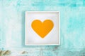 Yellow paper heart in white cardboard box on old turquoise metal background