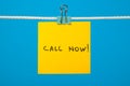 Yellow paper note on clothesline with text Call Now! Royalty Free Stock Photo