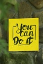 Yellow paper note with phrase You Can Do It on stone background Royalty Free Stock Photo