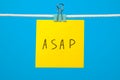 Yellow paper note on the string with text ASAP Royalty Free Stock Photo