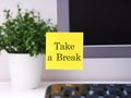 Yellow paper note with words Take a Break sticked on to a monitor at an office workplace