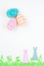 Yellow paper texture with green felt grass, bunny and colorful eggs, Easter background in pastel colors, vertical, copy space Royalty Free Stock Photo